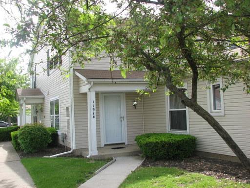 Front view of a two-story house with a white entrance door and light-colored siding.