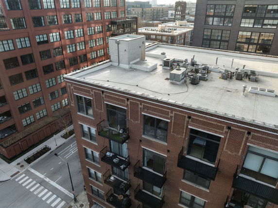Rooftop view of a brick building with HVAC units and other equipment.