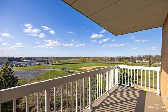 View from a balcony overlooking a park and sports fields with a clear blue sky.