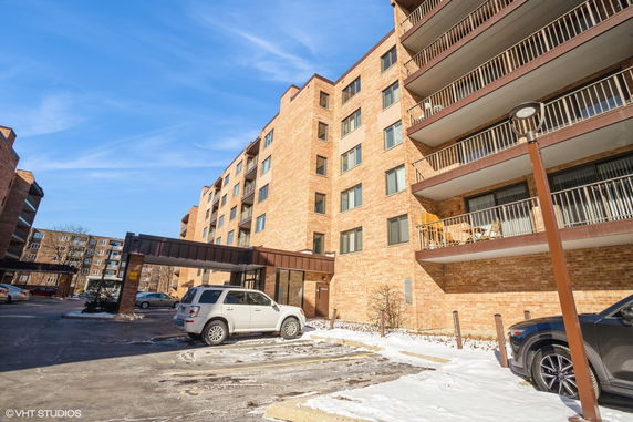 Front view of a multi-story brick apartment building with balconies.