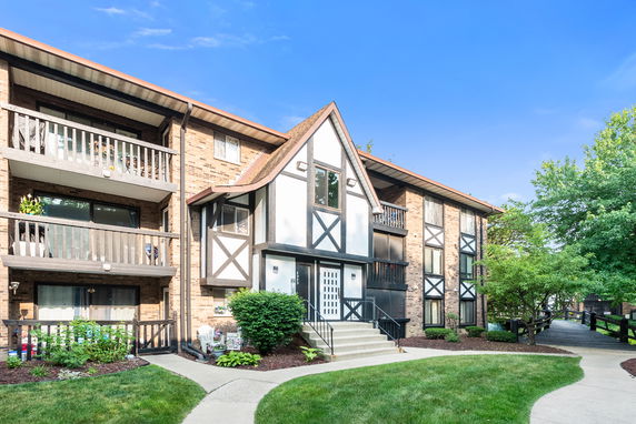 Front view of an apartment building with a Tudor-style facade and balconies.