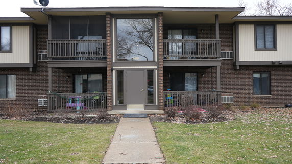 Front view of a two-story brick apartment building with balconies.