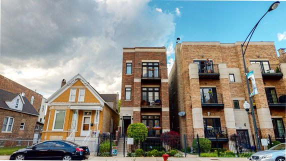 Front view of two brick buildings, one with a three-story design and balconies.