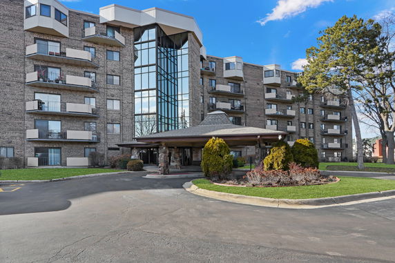 Front view of a multi-story residential building with balconies and a covered entrance.
