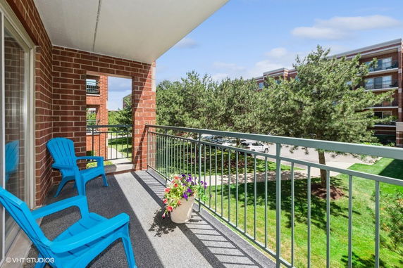 View from a balcony overlooking a parking area and trees.