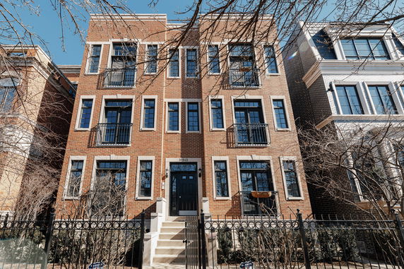 Front view of a multi-story brick building with multiple windows and a black front door.