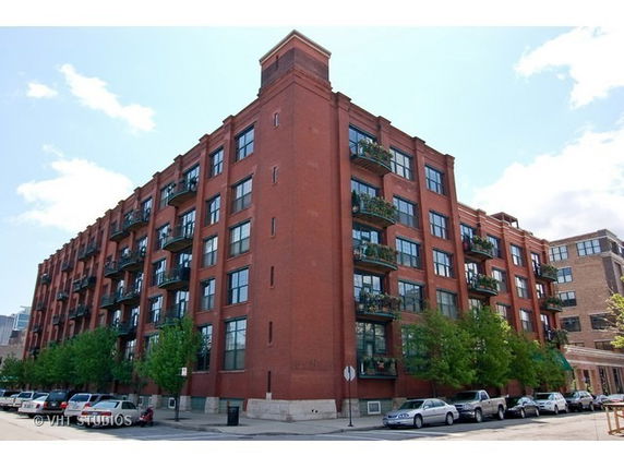 Front view of a multi-story apartment building with red brick facade and numerous windows.