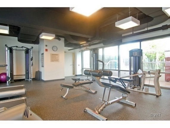 Indoor gym with various exercise equipment and large windows.