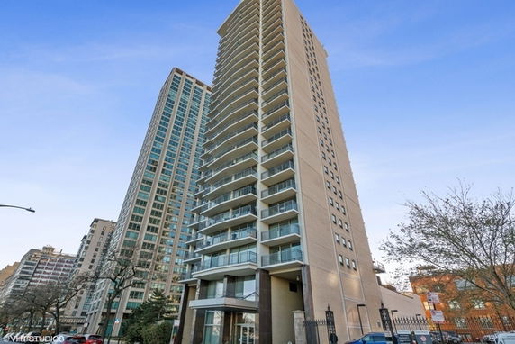 Front view of a tall residential building with multiple balconies.