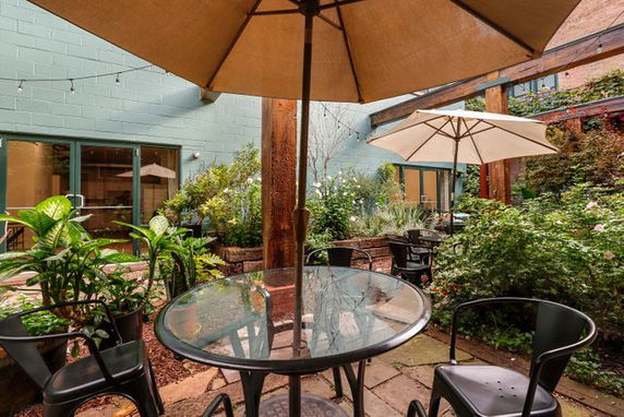 Outdoor seating area with glass table and umbrellas in a garden setting.