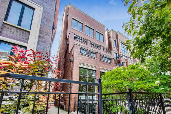Front view of a multi-story brick building with large windows and metal railings.