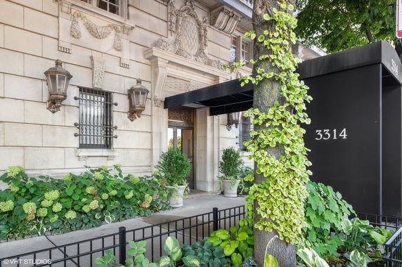 Front view of a building entrance with decorative elements and a black awning.