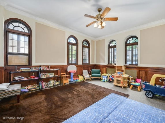 Room with toys and children's play furniture, featuring multiple arched windows.