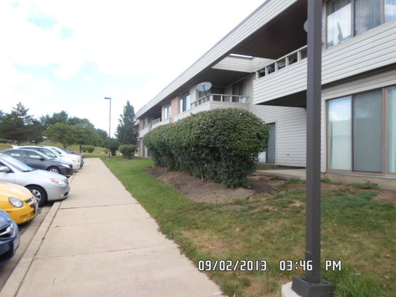 Front view of a two-story building with a row of windows and hedges along the sidewalk.