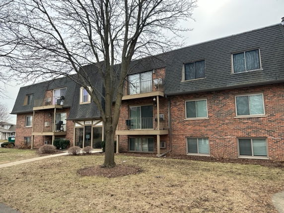 Front view of a multi-story brick apartment building with balconies.