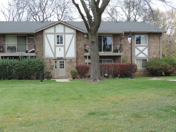 Front view of a multi-story building with a brick facade and wooden trim.