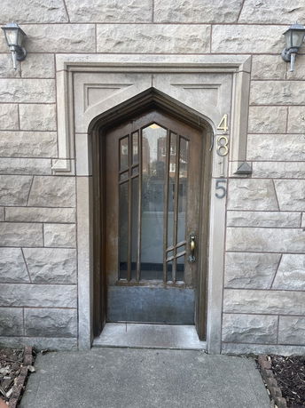 Front view of a stone building entrance with a wooden and glass door.