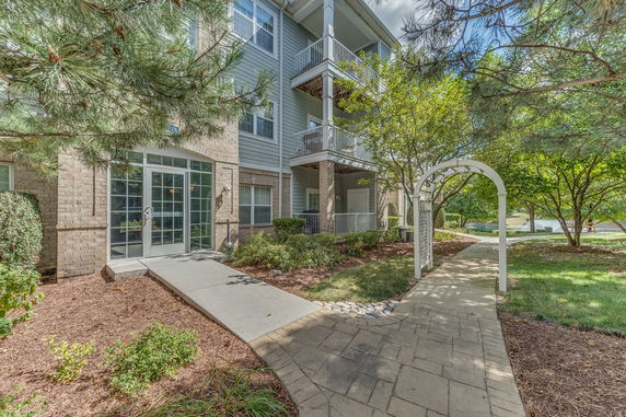 Front view of a multi-story apartment building with balconies and glass entrance doors.