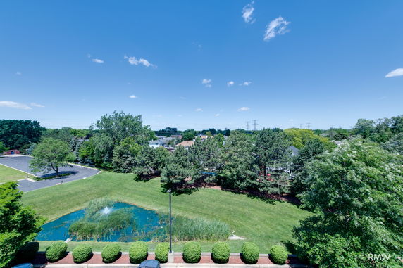 Panoramic view of surrounding areas featuring a pond, trees, and a grassy field.