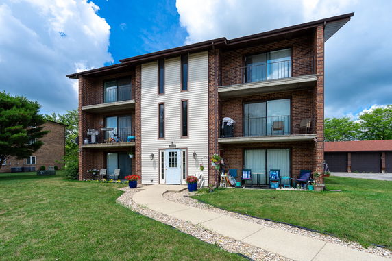 Front view of a three-story residential building with balconies and a central entrance.