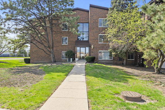Front view of a three-story brick building with large windows and a central entrance.