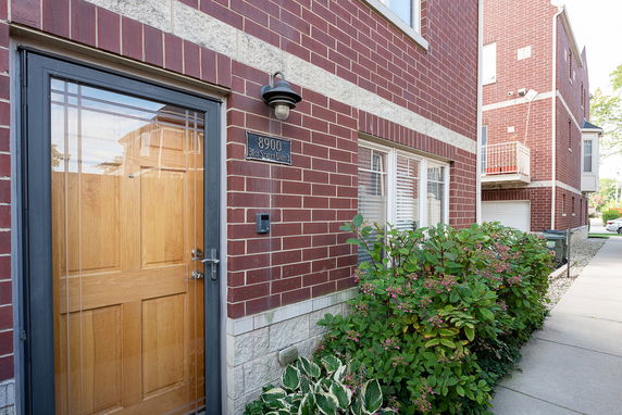 Front view of a brick residential building with a wooden door and number plaque.