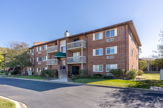 Front view of a multi-story brick apartment building with balconies.