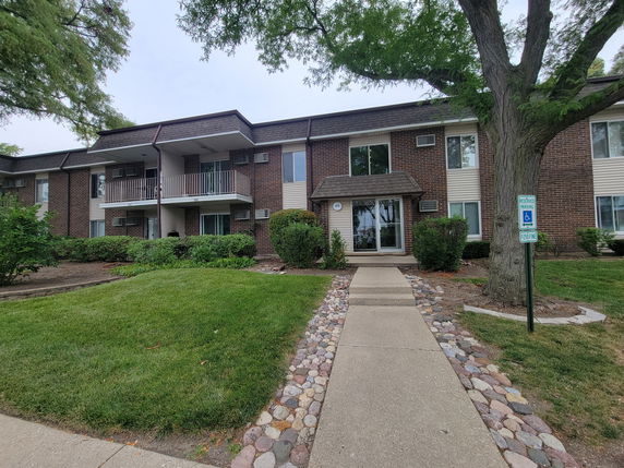 Front view of a multi-story brick building with balconies and pathway.