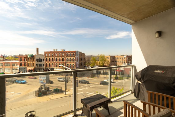 View from a balcony overlooking a city street with several buildings.