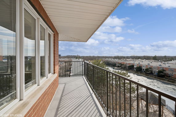 View from a balcony overlooking residential buildings and distant landscape.