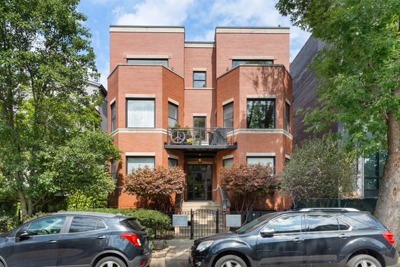 Front view of a three-story brick house with large windows and a small balcony.