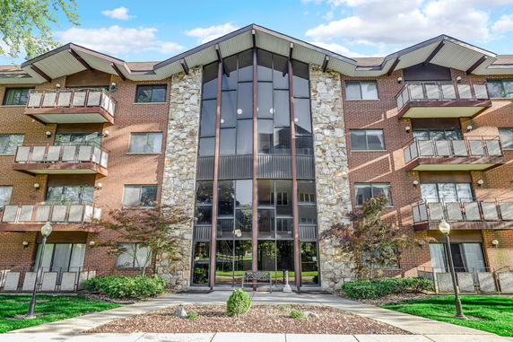 Front view of a multi-story building with glass entrance and balconies.