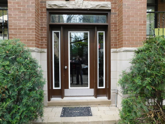 Front entrance of a building with a glass door and brick facade.