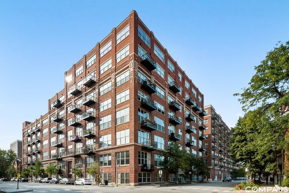Front view of a multi-story brick apartment building with balconies.