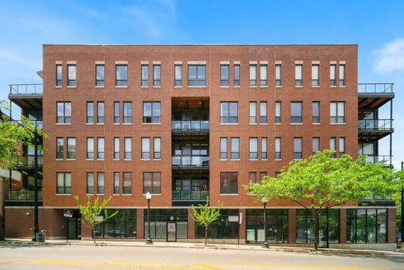 Front view of a multi-story brick building with large windows and balconies.