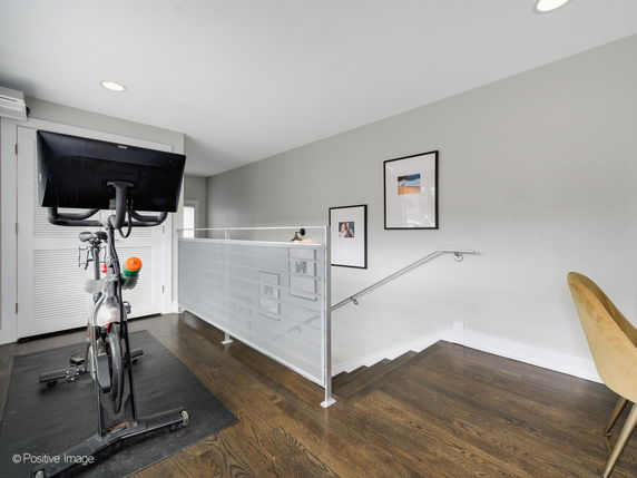 Indoor area featuring a stationary exercise bike on a wooden floor with framed pictures on the wall.