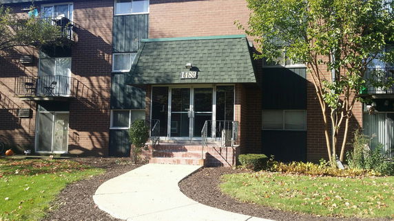 Front view of a multi-story brick apartment building with balconies and a central entrance.