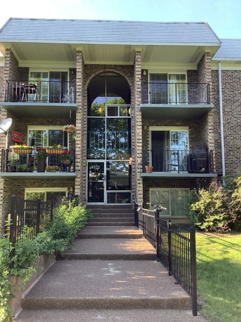 Front view of a multi-story building with balconies and a central glass entrance.