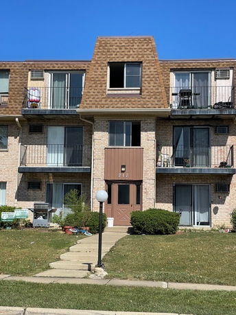 Front view of a three-story apartment building with balconies and a central entrance.
