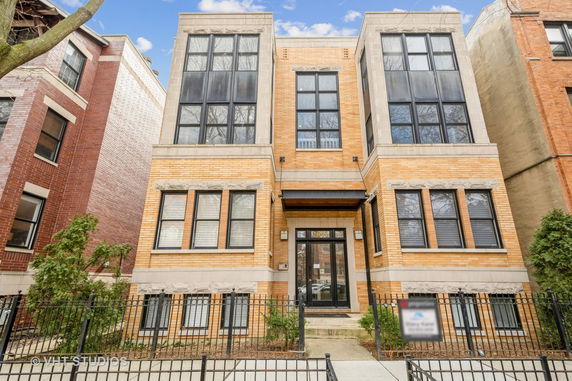 Front view of a multi-story brick building with large windows.