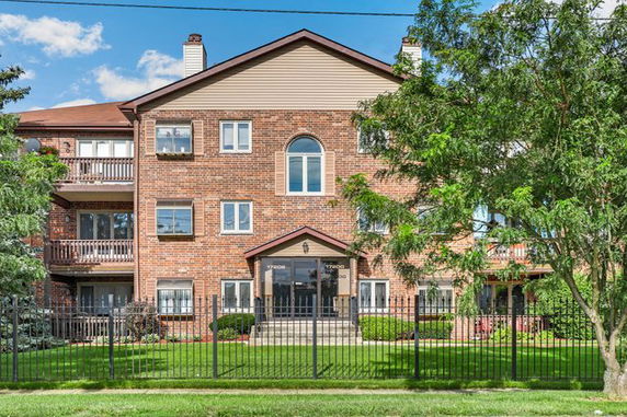 Front view of a multi-story brick residential building with balconies.