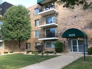 Front view of a multi-story brick apartment building with balconies and a green awning entrance.