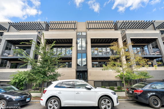 Front view of a multi-story residential building with balconies and modern design elements.
