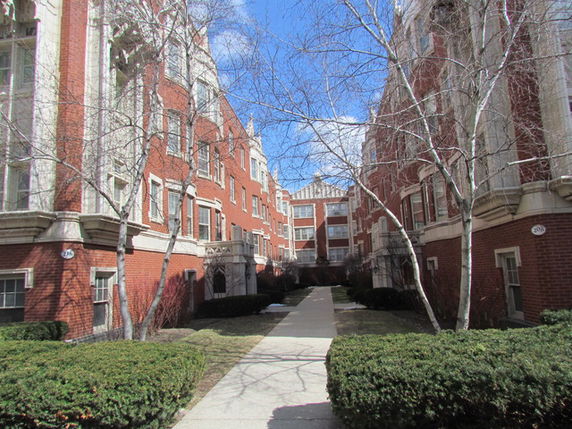 Front view of multi-story brick apartment buildings with a central path.