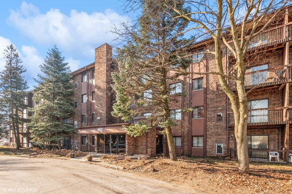 Front view of a multi-story brick residential building with balconies.
