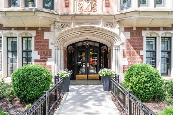 Front view of a building entrance with decorative architectural details and a pathway.