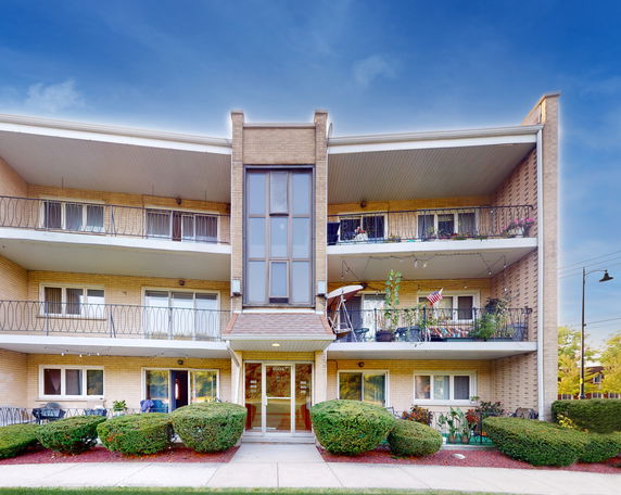 Front view of a multi-story apartment building with balconies and glass entrance.
