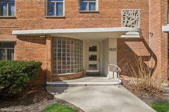 Front entrance of a brick building with glass block wall and number 1862.