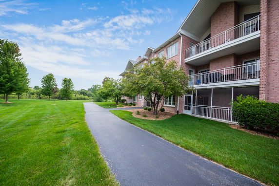 Front view of a multi-story brick building with balconies and a paved walkway.