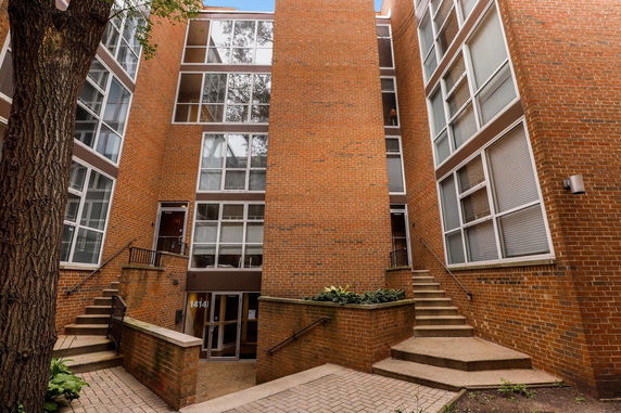 Front view of a multi-story brick building with large windows.